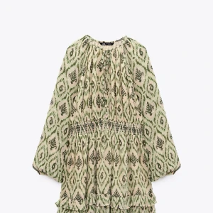 Grönmönstrad volangklänning från Zara - Säljer en luftig kortklänning från Zara med grönt och beige mönster. Klänningen har långa ärmar, smock i midjan och volangdetaljer nertill. 