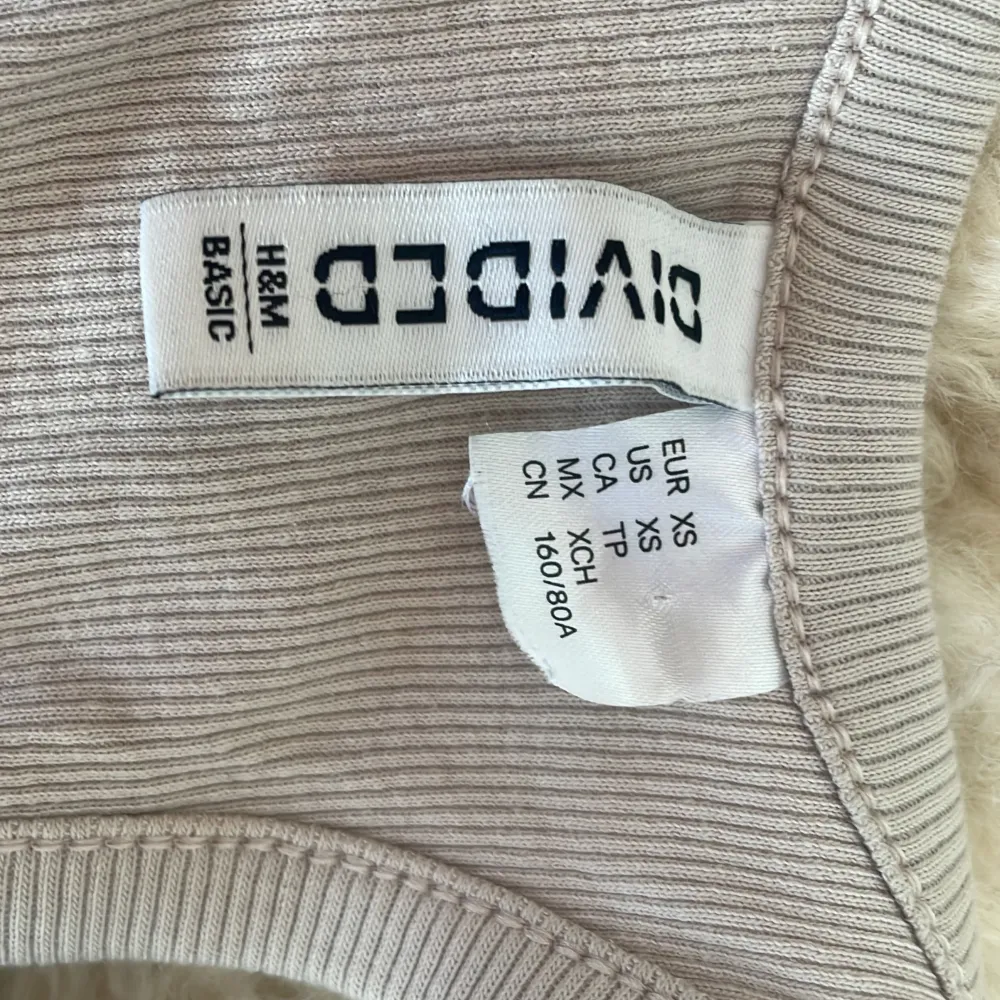 Säljer en beige ribbad linnetopp från H&M Divided. Toppen är ärmlös med rund halsringning och har en tight passform. Perfekt för varma dagar eller som layering-plagg. Superenkel att matcha med både kjol och jeans.. Yläosat.