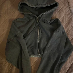 Svart croppad hoodie med dragkedja - Säljer en svart croppad hoodie med dragkedja framtill och huva med dragsko. Perfekt för en avslappnad stil och passar bra till jeans eller träningsbyxor. Knappt använda då jag inte gillar hur den sitter på mig 🩵