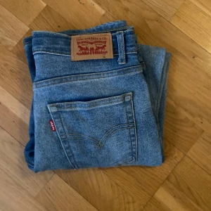 Levis blå jeans - Klassiska blå Levis jeans med rak passform och femficksdesign. Byxorna har normal midja och en loose fit. Perfekta för en tidlös och avslappnad stil. Storlek 164, köp gärna i bundle 