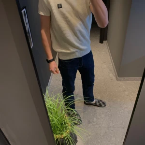 Vit stickad väst från Lagency - Snygg vit stickad väst från Lagency. Den har en rund halsringning och ett diskret märke på bröstet. Perfekt för lager-på-lager-stil. Storlek Small