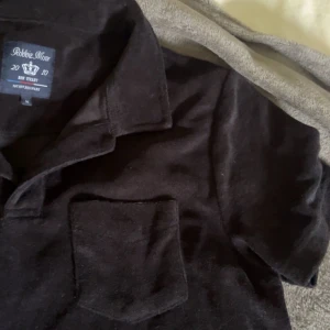 Svart pikétröja från Robbie Moor - Klassisk svart pikétröja från Robbie Moor i frottématerial, använd få gånger