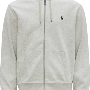 Ljusgrå hoodie med dragkedja från Polo Ralph Lauren - Säljer en stilren ljusgrå hoodie från Polo Ralph Lauren med dragkedja framtill och två fickor. Tröjan har huva med snörning och en broderad logga på bröstet. Perfekt för en avslappnad look.