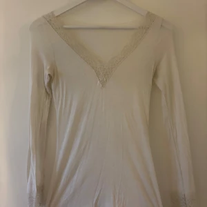Vit långärmad topp med spetsdetaljer från Intimissimi Stl: S - Supersöt vit långärmad topp från Intimissimi med v-ringning och fina spetsdetaljer. Använd endast ett fåtal gånger så i bra skick