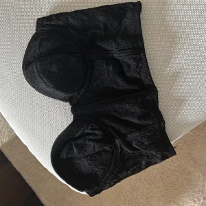 Svart spetsig korsett från Sisters Point - Säljer en svart korsett från Sisters Point i storlek XS. Toppen är täckt av spets och har vadderade kupor samt hysk- och hakknäppning bak. Perfekt för att lyfta din outfit med en trendig och feminin touch.