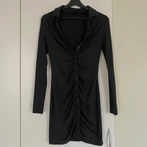 Klänning - Stretchig svart klänning, knapparna nertill sitter fast medan knapparna överst är knäpp-bara