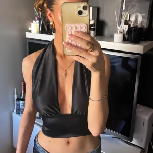 Svart halterneck topp i satin - Säljer en svart halterneck topp i satin material .passar xs och s då man kan justera med banden. 