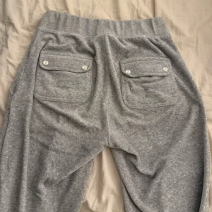 Juicy Couture byxor  - Jättefina Juicy byxor i grå färg. Snörena är borta och ett hål finns på ena fickan bak men inget som syns vid användning.