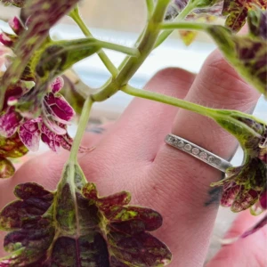 Äkta silverring med stenar - Säljer en stilren silverring med infattade klara stenar runt hela ovansidan. Ringen är i äkta silver (stämplad 925) och har en enkel, tidlös design som passar perfekt för dig som gillar diskreta smycken. Lite repig och deformerad (syns ej när ringen är på).
