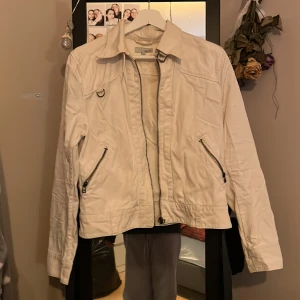 Vit jacka med dragkedjor - Säljer en stilren vit jacka från hennes med dragkedjor på fickorna och detaljer vid kragen. Passar mig som har storlek s-m perfekt