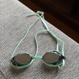 Mintgröna simglasögon - Snygga mintgröna simglasögon med spegelglas och svart detalj på sidorna. Justerbart band för perfekt passform. Perfekta för simträning,  tävling eller bara poolen.