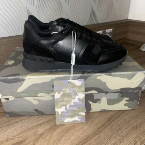 Svarta Valentino Garavani sneakers - Säljer ett par svarta Valentino Garavani skor i storlek 39. Dom är i helt nytt skick och du får med alla saker som ingår så som låda osv. Dm:a om förslag på pris..