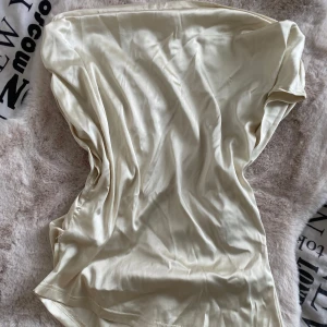 Champagnefärgad tröja  - Elegant champagnefärgad tröja i siden med en mjuk och glansig yta. Perfekt för en stilren look.