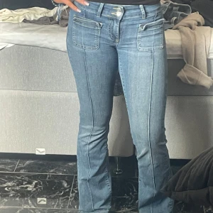 Blå bootcut jeans - Snygga blå bootcut jeans med låg midja  och framträdande fickor fram. Perfekta för en avslappnad stil med en touch av retro. Passar bra till både sneakers och klackar. 