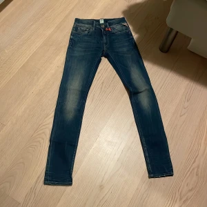 Blå jeans från Replay - Snygga blå jeans från Replay med en tight passform. De har en klassisk femficksdesign och en lätt slitning för en cool look. Perfekta för en avslappnad stil.