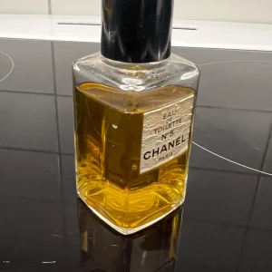 Chanel N°5 Eau de Toilette.Vintage! - Elegant flaska med den ikoniska Chanel N°5 Eau de Toilette. Den har en klassisk rektangulär form med en svart kork och en gyllene vätska inuti. Perfekt för den som älskar tidlös och sofistikerad doft.