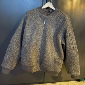 Grå bomberjacka - Säljer en snygg grå bomberjacka med dragkedja och ribbade muddar. Storlek M