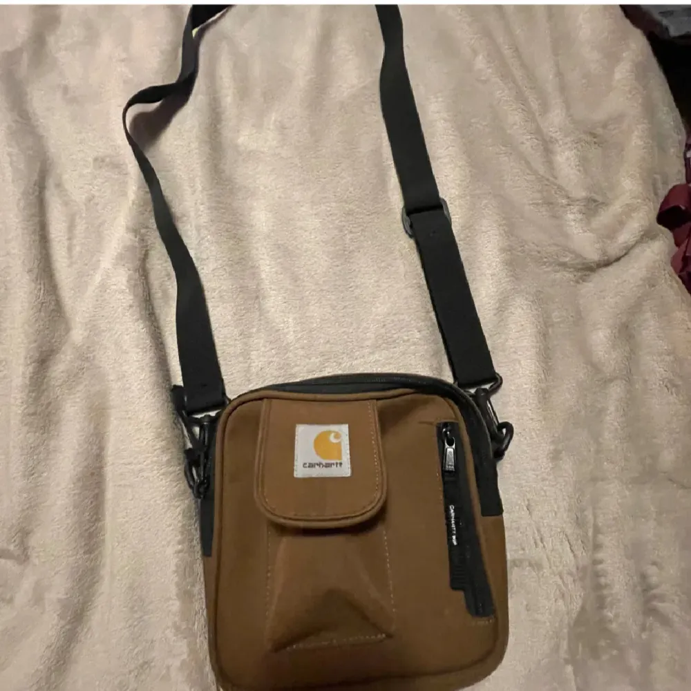 Säljer en snygg brun axelväska från Carhartt. Väskan har en justerbar svart axelrem och en praktisk dragkedja. Perfekt för att bära med sig det nödvändigaste. . Laukut & Käsilaukut.