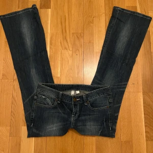 Mörkblå bootcut jeans - Snygga mörkblå bootcut jeans med klassisk femficksdesign och lätt slitna detaljer. Perfekta för en avslappnad stil med en touch av retro. De har en knapp och dragkedja framtill.