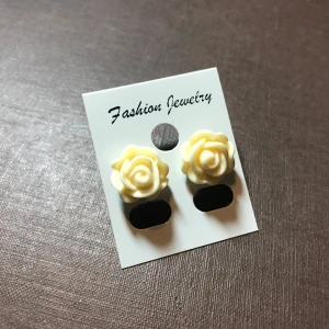 Krämfärgade rosformade örhängen - Säljer ett par söta krämfärgade örhängen formade som rosor. Perfekta för att ge en romantisk touch till din outfit. De är små och eleganta, vilket gör dem lätta att bära till olika tillfällen.