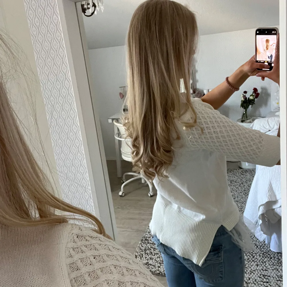 Säljer en stilren vit ribbad topp med trekvartsärm och spetsdetaljer på ärmarna. Toppen har en unik design med en volangkant i tyll vid nederkanten. Perfekt för att ge en romantisk touch till din outfit.. Neuletakit & Villapaidat.