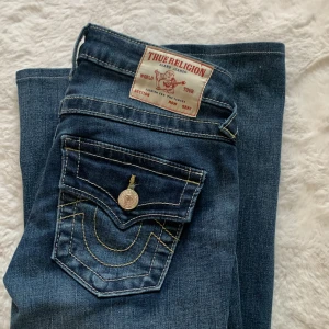 true religon jeans !!💙 - Snygga blå jeans från True Religion med låg midja och flare-stil. De har en klassisk femficksdesign och dekorativa sömmar på bakfickorna. Perfekta för en avslappnad look. I storlek w23 . De är endast provade .🩷modellen joey! Priset kan diskuterats vid snabb affär !