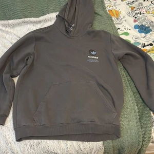 Grå hoodie från Adidas - Säljer en grå hoodie från Adidas med stor logga på ryggen och mindre logga på bröstet. Köpte på Jd i mall of Scandinavia