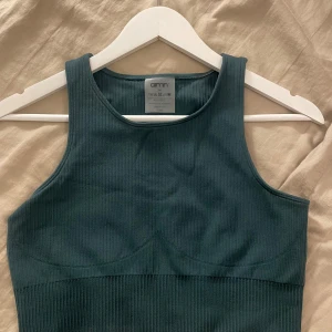 Grön ribbad linnetopp från amin - Snygg grön ribbad linnetopp från amin. Perfekt för en stilren och bekväm träning. Tillverkad i en blandning av polyamid och elastan för en stretchig passform.