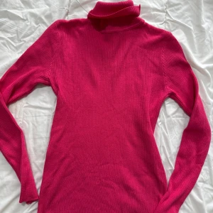 Rosa kofta med hjärtmönster - Söt rosa kofta med hjärtmönster i en ljusare nyans. Koftan har knappar framtill och två fickor. Perfekt för en mysig dag.