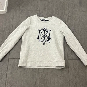 Grå tröja från Morris Lady - Säljer en stilren grå tröja från Morris Lady med ett elegant mörkblått broderat mönster på framsidan. Tröjan har långa ärmar och en rund halsringning. Perfekt för en avslappnad men snygg look. Nypris  1399kr Postar inom 24h, pris kan diskuteras bredd 25cm längd 45cm