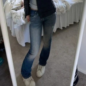 Blå bootcut jeans - Snygga blå bootcut jeans med en klassisk femficksdesign. De har en lätt slitning på låren och knäna för en trendig look. Perfekta för en avslappnad stil. Gjort hålen själv.