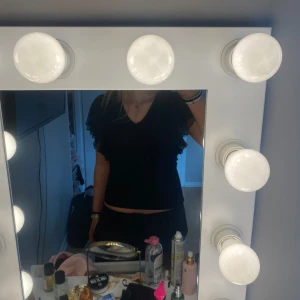 Svart topp med volangärmar från Holly & Whyte - Svart topp från Lindex med v-ringning och volangärmar i spets. Strl S