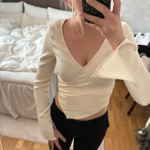 Vit satinblus  - Säljer en vit satinblus med v-ringning och långa ärmar. Blusen har en elegant design med utsvängda ärmar och slit. Skulle säga att blusen är lite mindre i storleken🤍