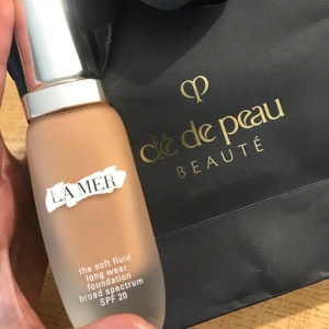 Foundation från La Mer - Säljer en lyxig foundation från La Mer, 'The Soft Fluid Long Wear Foundation' med SPF 20. Den har en elegant glasflaska med silverfärgat lock. Perfekt för en jämn och hållbar täckning.