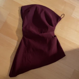 Vinröd asymmetrisk tubtopp från Zara - Snygg vinröd tubtopp från Zara med en unik asymmetrisk design. Storlek M men själv brukar jag ha xs-s och dennä är för liten för mig. Alldrig andvänd💕