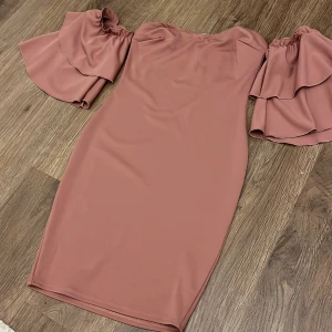 Rosa offshoulder klänning - Snygg rosa offshoulder klänning med volangärmar. Perfekt för en somrig look. Klänningen har en tight passform som framhäver figuren.