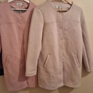 Långärmad kappa från ONLY - Säljer en stilren långärmad kappa från ONLY. Finns i tre färger: rosa, beige och svart kappan har en rund halsringning och knäpps med knappar framtill. Perfekt för vår och höst!
