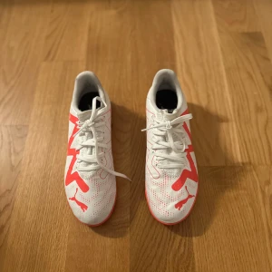 Vita och röda fotbollsskor från Puma - Snygga inomhusfotbollsskor från Puma i vitt med röda detaljer och snörning. Skorna har en mönstrad sula för bra grepp på planen. Perfekta för inomhusfotboll eller träning. Skorna är använda men inga skador. Skorna tvättas rent och noga innan jag skickar de, hör av er för mer bilder💓😍🙏🏼