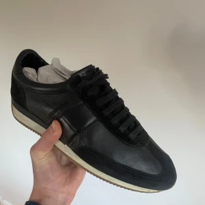 Svarta sneakers från Tom Ford - Snygga svarta sneakers från Tom Ford i skinn med stilren design. Köpte från Vestaire och bara använde ett par månader. Topp skick.✅ Storlek 43✅Rikigt bra kvalitet på skorna och otroligt sköna att ha till vardagen 🙌🏼