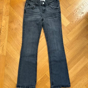 Grå lågmidjade bootcut jeans från Zara - Snygga low waisted grå bootcut jeans från Zara. Jeansen har en fransig kant vid bensluten, det är alltså fabrik slitage som redan fanns när jag köpte dem