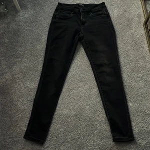 Svarta jeans från Toxik3 - Snygga svarta jeans från Toxik3 med en tight passform. De har klassisk femficksdesign och stängs med dragkedja och knapp. Perfekta för en stilren look.