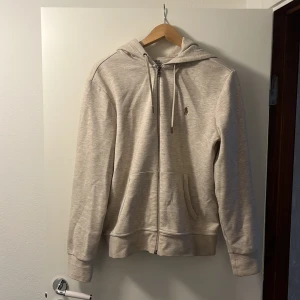 Ralph lauren hoodie beige - Säljer en stilren beige hoodie från Polo Ralph Lauren. Den har en dragkedja framtill och en liten broderad logga på bröstet. Den är i bra skick.