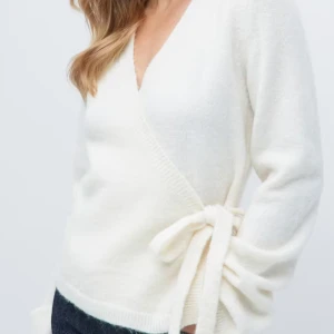 Vit omlottkofta med knytband - Säljer en stilren vit omlottkofta med knytband i midjan. Koftan har en v-ringad design och långa ärmar, perfekt för en elegant och bekväm look. Passar bra till både jeans och kjol.