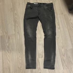 Gråa Replay Anbass jeans   - Snygga gråa jeans från Replay med en slim passform. Byxorna har en klassisk femficksdesign och dragkedja. Perfekta för en stilren look. Lite slitningar men inga hål. 