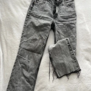 Grå jeans från Zara - Snygga grå jeans från Zara med en slits ner på båda benen. De har en dragkedja och knapp framtill samt klassiska fem fickor. Perfekta för en avslappnad stil. Medelmidja/högmidja. Bilder på kan skickas om intresse.