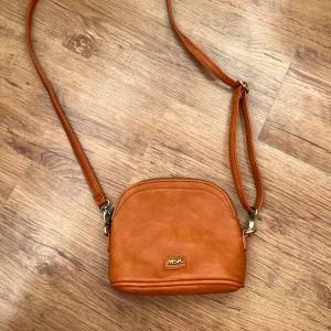 Snygg väska 💼  - Säljer en snygg brun axelväska från MSK i syntetmaterial. Väskan har en justerbar axelrem och en praktisk dragkedja på baksidan. Insidan är fodrad med ett blommigt mönster i mjuka färger. Perfekt för att bära dina nödvändigheter med stil!