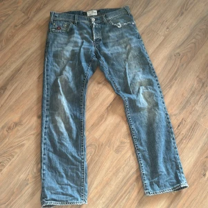 Blå jeansbyxor från Energie - Säljer ett par klassiska blå jeansbyxor från Energie. De har en straight fit och är tillverkade i slitstarkt denim. Byxorna har en knappgylf och fem fickor, med en liten sliten detalj vid ena fickan för en cool look.