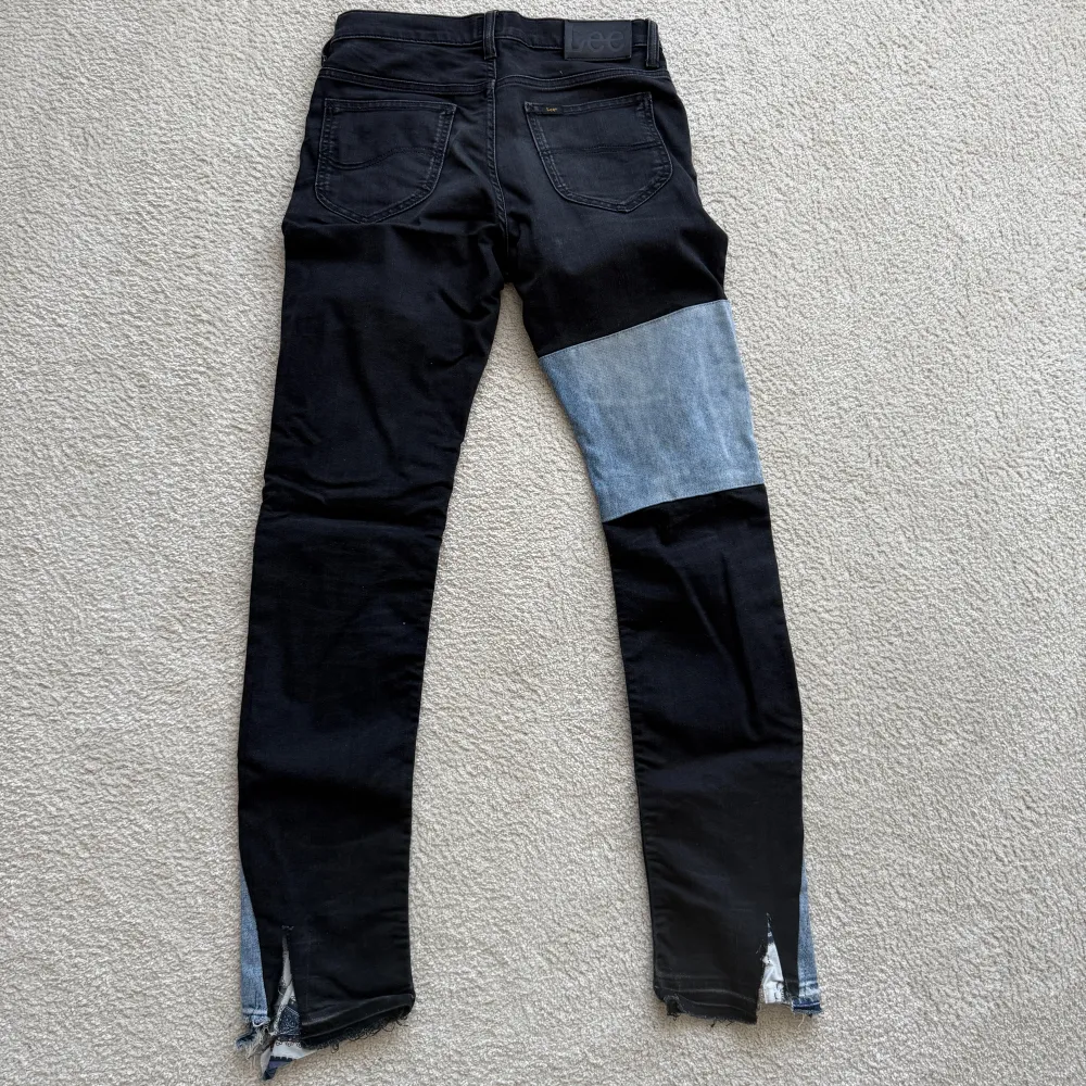 Unika svarta jeans med ljusblå patchwork-detaljer och slitna kanter. Byxorna har en skinny passform och är högmidjade. Perfekta för en edgy look!. Farkut & Housut.