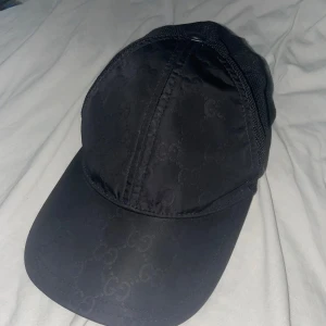 Svart keps - Snygg svart keps med diskret mönster. Perfekt för en stilren look. Kepsen har en klassisk design med böjd skärm och justerbar passform.