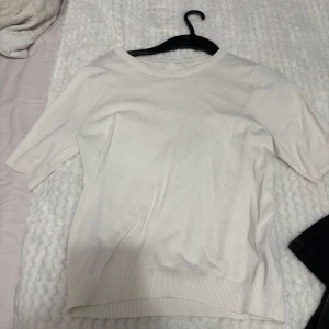 Vit kortärmad tröja från H&M - Säljer en stilren vit tröja från H&M med korta ärmar och rund hals. Perfekt för en enkel och klassisk look. Tröjan är i ett mjukt material som känns skönt mot huden. Använd 2 gånger max